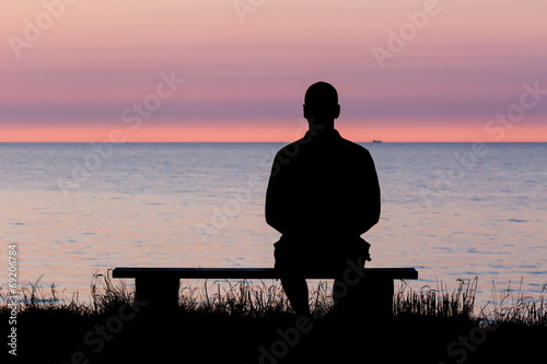 Silhouette of man on bench photo