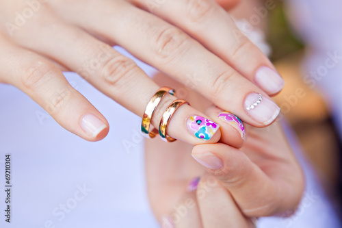 Wedding ring on the finger of a bride with a colored nail polish