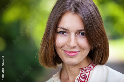 Closeup of young beautiful woman in summer park smiling