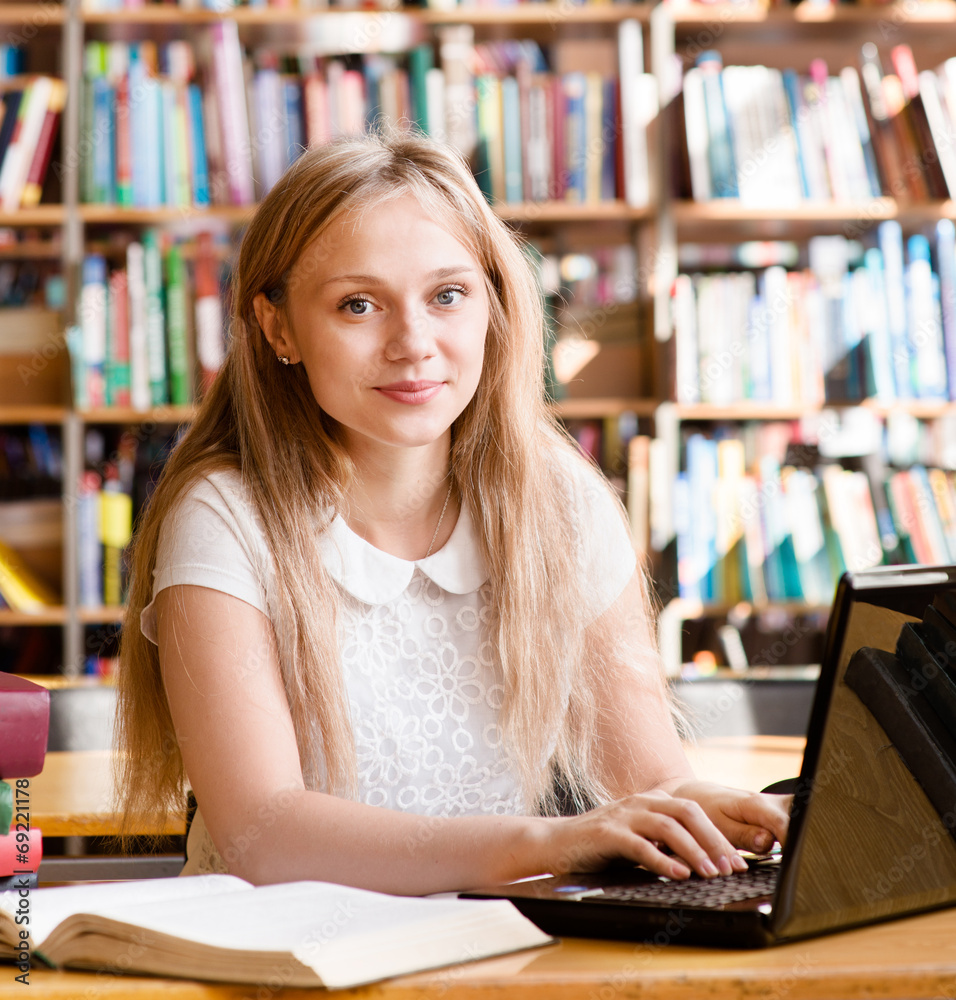 Portrait of a pretty female student with laptop in library Portrait of a pretty female student with laptop in library
