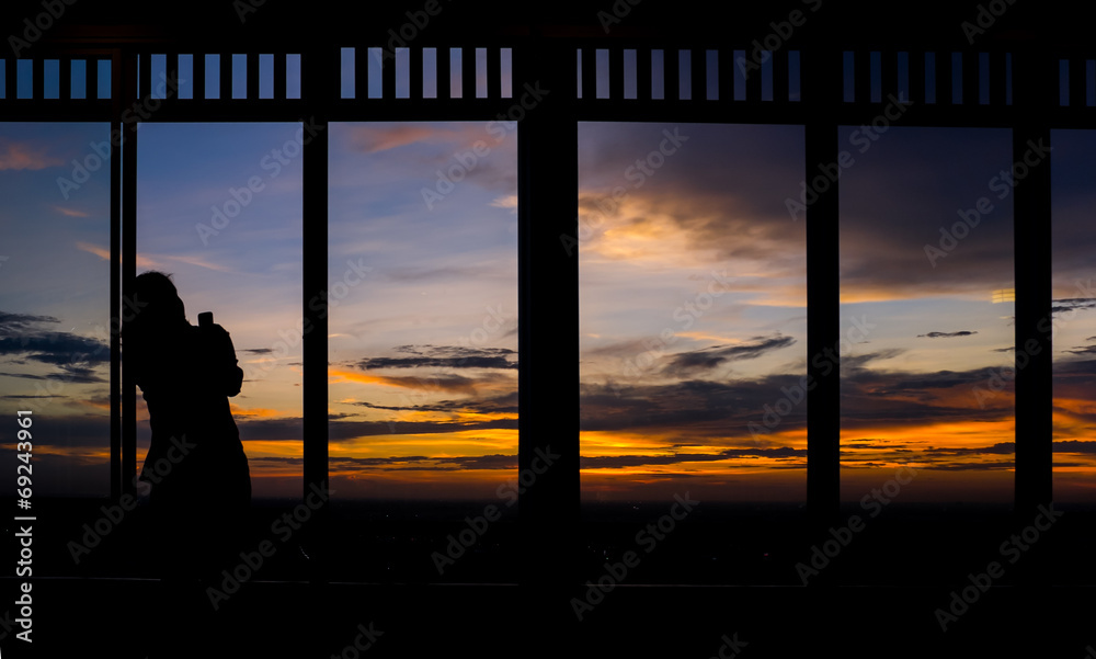 Girl using smart phone taking photo of twilight sky at sunset