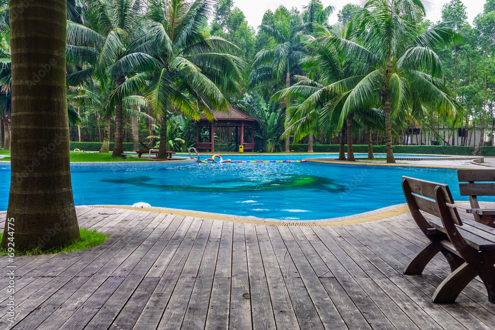 Swimming pool with hut and wooden pool deck in garden of resort Swimming pool with hut and wooden pool deck in garden of resort