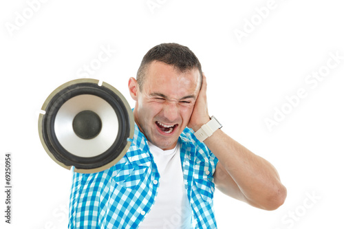 Man listening to loud music holding speaker and covering ears