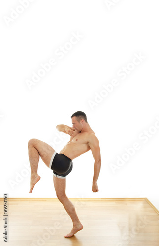 Powerful muscular sports guy standing in fight position kicking