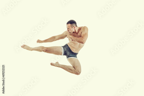 One caucasian man exercising boxing jumping in the air kicking