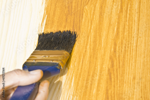 Woman hand with paintbrush on wood.