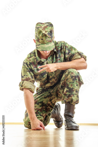 soldier in camouflage uniform and hat kneeling on the floor and