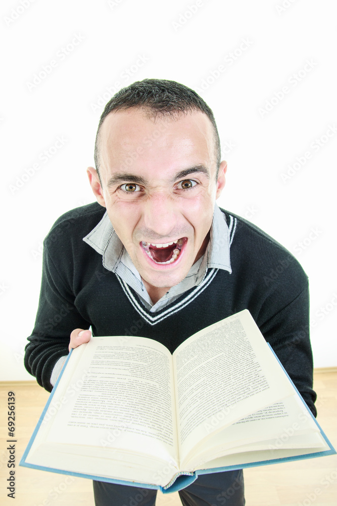 Angry young man holding a book tired of reading Angry young man holding a book tired of reading