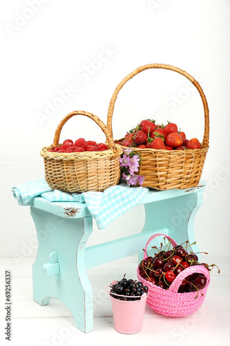Fresh berries in baskets on white wall background © Africa Studio