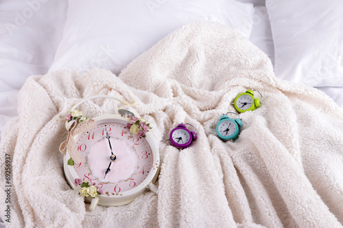 Metal clocks on pillows on a big white bed