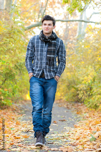 Smiling man walking in autumn park.