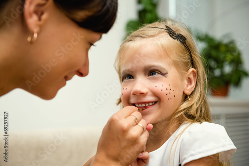 Женщина раскрашивает лицо ребенка к празднику