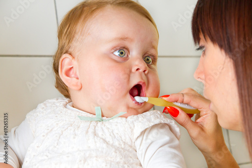 Mutter putzt Zähne ihres Babys photo