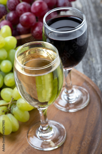 glasses of white and red wine, fresh grapes on a wooden board