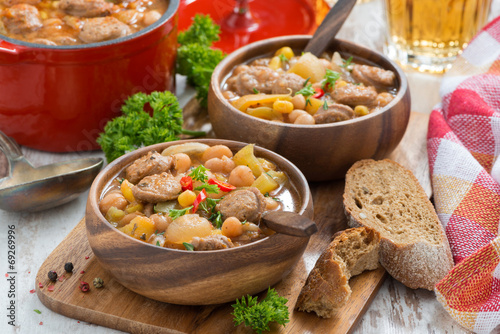 vegetable stew with sausages in a wooden bowl on board and bread