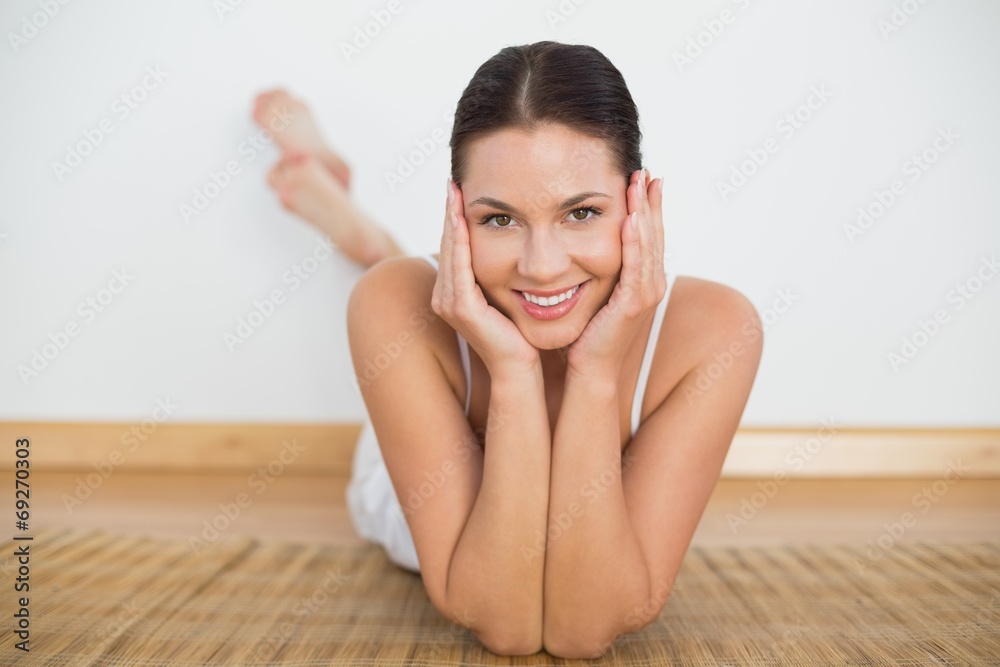 Smiling brunette lying on floor looking at camera Smiling brunette lying on floor looking at camera
