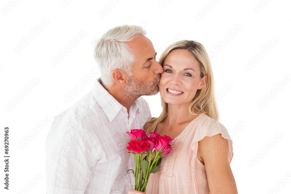 Affectionate man kissing his wife on the cheek with roses