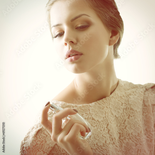 Girl with perfume, young beautiful woman holding bottle of perfu photo