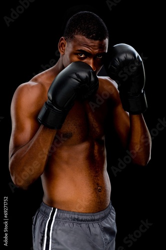 Portrait of a shirtless muscular boxer in defensive stance © WavebreakMediaMicro