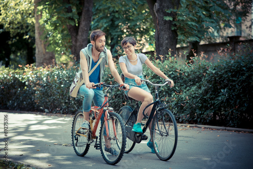 couple of friends young  man and woman riding bike