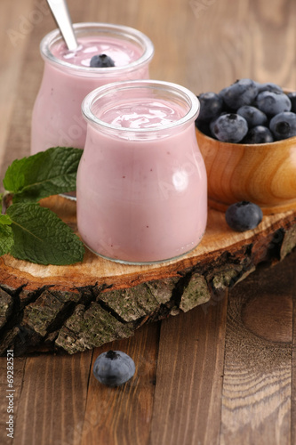 yogurt with blueberries in a glass jar and blueberries in a wood