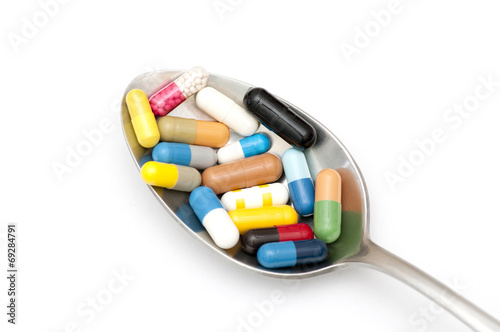 Assortment of capsules in table spoon on white