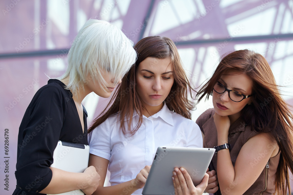 a group of businesswomеn from tablets on the street
