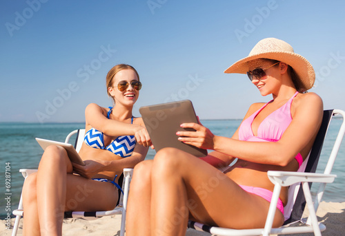 smiling women with tablets pc computers on beach © Syda Productions