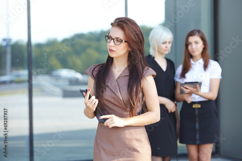 a group of businesswomеn from tablets on the street