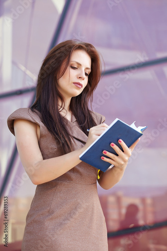 beautiful business woman on the street with blue notepad