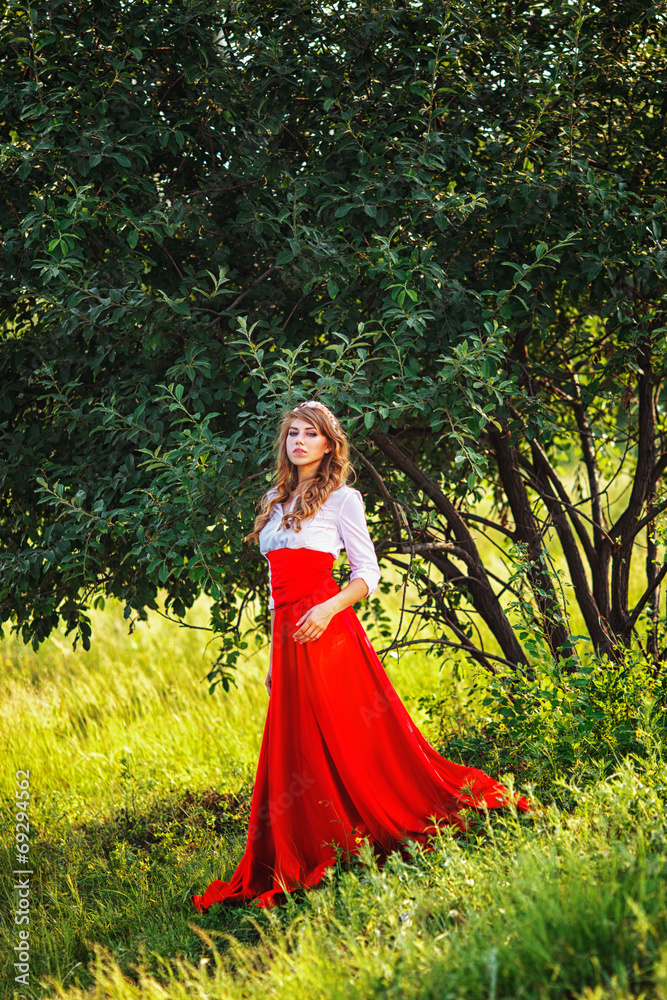 woman in red skirt standing under the tree