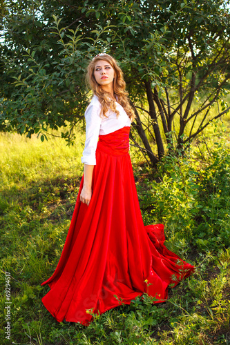 woman in red skirt standing under the tree