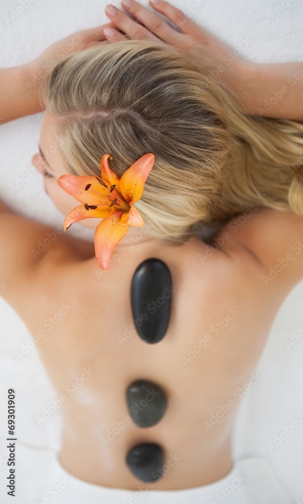 Beautiful blonde enjoying a hot stone massage - obrazy, fototapety, plakaty 