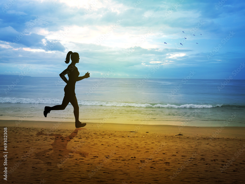 Silhouette of a female figure jogging at the beach