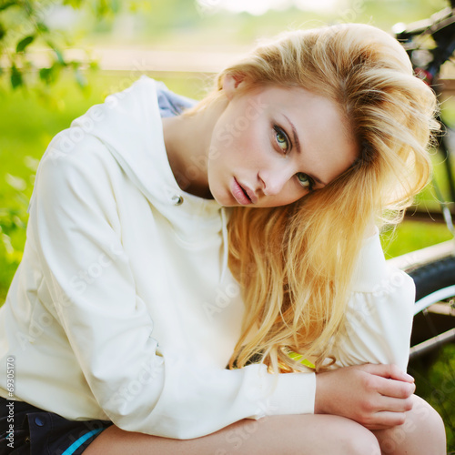 Beautiful girl sitting against bike outdoor in the park photo