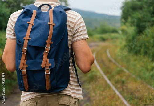 Hiker man with backpack going on path in summer