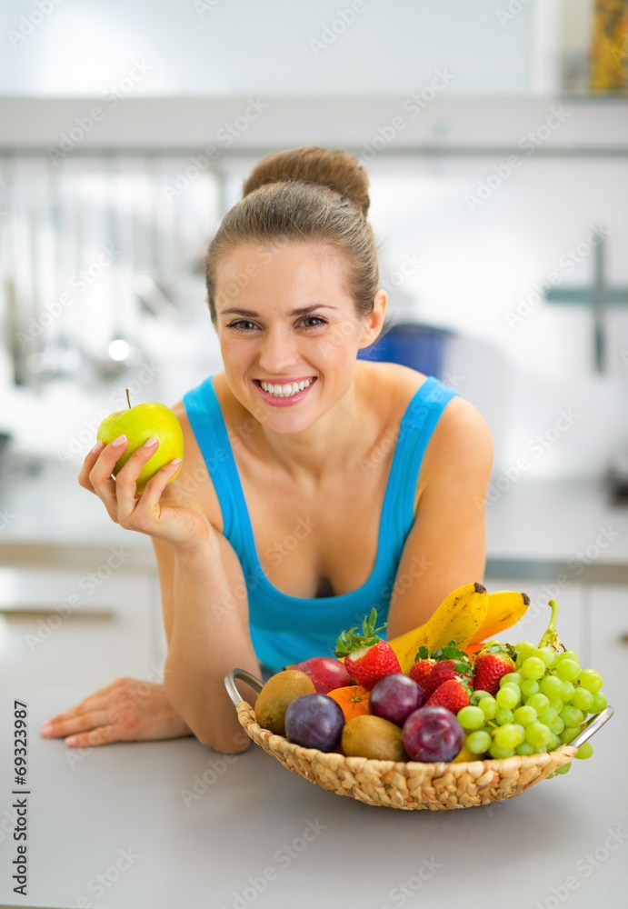 Happy young woman with fruits plate eating apple
