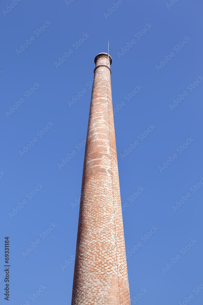 Old brick chimney against blue sky