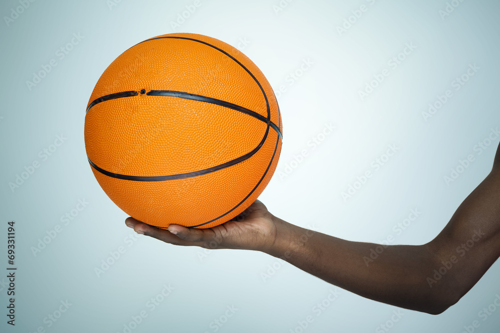 Hand holding a basket ball on gray background