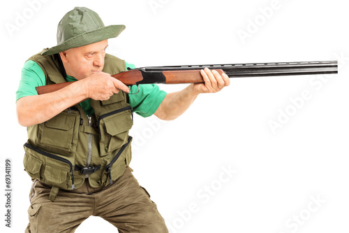 Mature hunter aiming at something with a gun