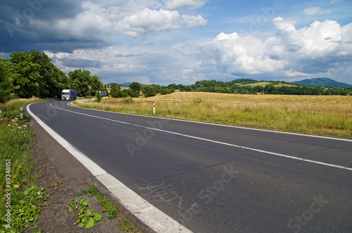 Obraz na płótnie Road in a rural landscape with dramatic clouds in the sky w salonie
