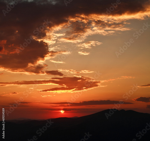 Dramatic sunset with clouds, in mountains, nature background © okostia
