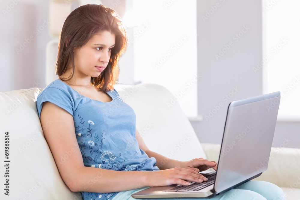 Pretty brunette relaxing on the couch using laptop Pretty brunette relaxing on the couch using laptop