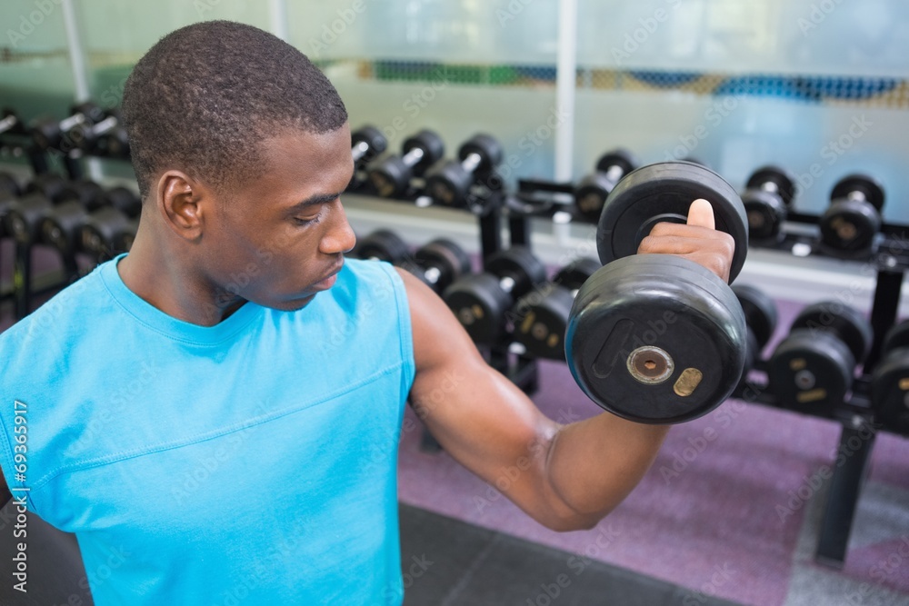 Young man exercising with dumbbell in gym Young man exercising with dumbbell in gym