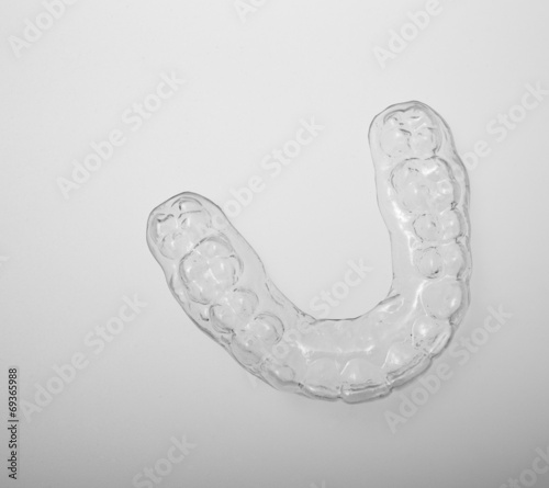 Translucent essix retainer placed on a gray background photo