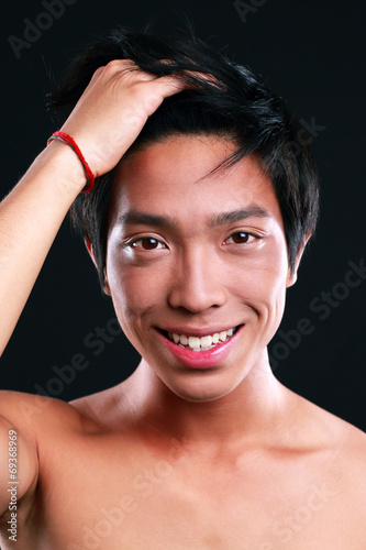 Portrait of a smiling asian man standing on black background