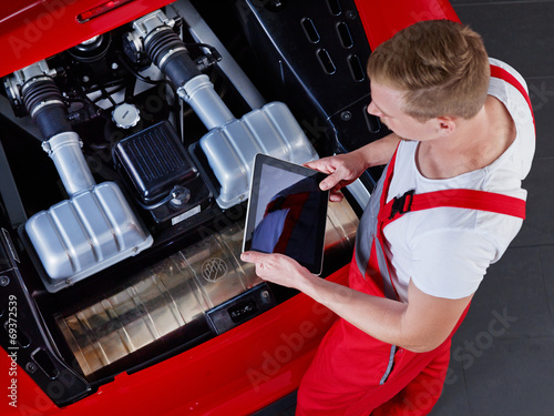 Mechanic inspecting the engine of a car with touchpad