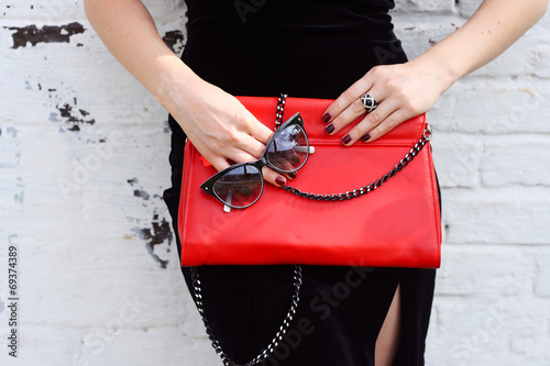 Fashionable woman with  stylish red clutch and sunglasses
