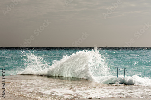 The waves breaking on a stony beach, forming a spray