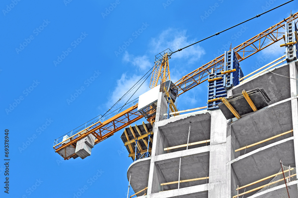 Fototapeta premium Crane and building construction site against blue sky